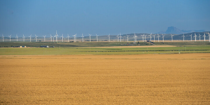 Wind turbines on a vast landscape with fields under a clear sky in the distance. Waterton Lakes National Park, Alberta, Canada