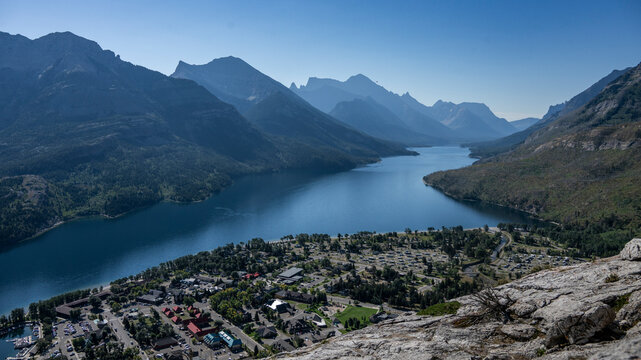 Scenic view of a mountain range and lake with a town nestled at the base. Waterton Park, Alberta, Canada