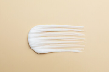 Sample of moisturizing cream on beige background, top view