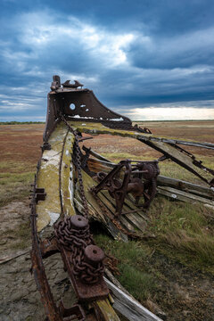 Rusted shipwreck on a grassy field under a dramatic, cloudy sky. Hudson Bay, Churchill, Manitoba, Canada