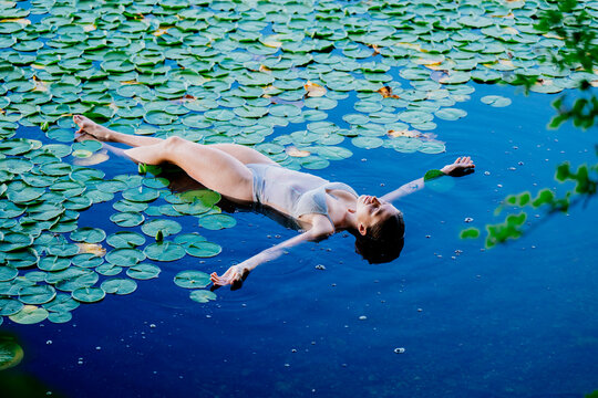 Woman floating peacefully on a serene lake surrounded by vibrant green lily pads. Wildcat Lake Park, WA, USA