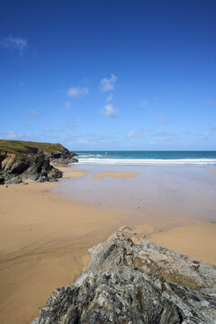 Porth Joke Beach, also known as Polly Joke, near Newquay, Cornwall, UK. Rocky coastal beach under clear blue sky with gentle waves and sandy shoreline.