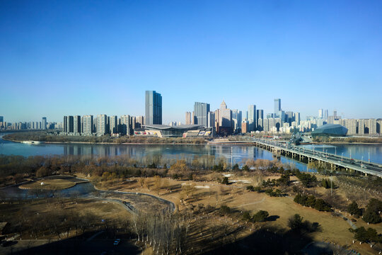 Shenyang, China, showing the skyline and Hunhe River. Skyline view of a modern cityscape with tall skyscrapers and a river under a clear sky.