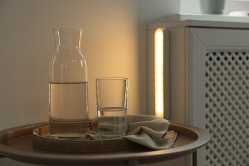 Table with water and portable LED lamp on wall at home
