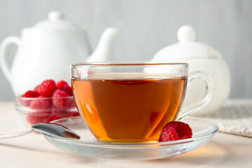 Delicious tea and raspberries on white table, closeup