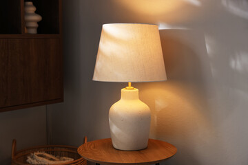 Stylish lamp on wooden table near light wall at home