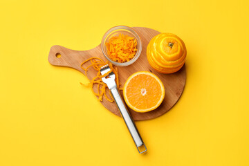 Orange zest, fresh fruits and zester tool on color background, top view