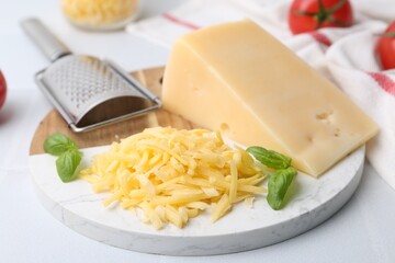 Grater, basil, grated and piece of cheese on white table, closeup