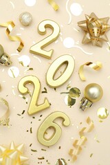 New 2026 Year. Golden numbers, shiny baubles and confetti on beige background, flat lay