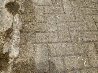 Close-up texture of old concrete paving blocks with dirt and worn surface, perfect for background or construction concept.