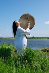 Shaman woman in a trance drumming outdoors