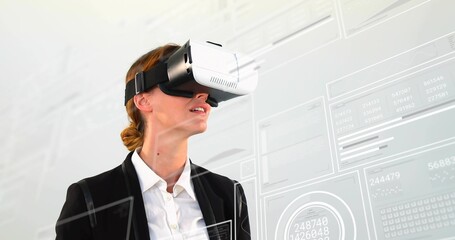 Interacting businesswoman wearing VR headset exploring data in studio, with translucent UI panels