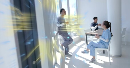 Chatting colleagues wearing scrubs and sipping ceramic mug and paper cup in hospital break room