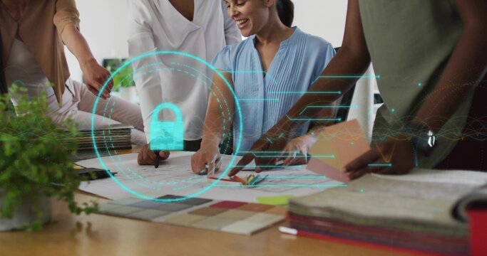 Four women collaborating over blueprints around table in studio, with holographic lock overlay