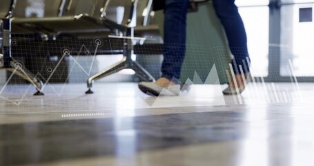Walking traveler pulling light green suitcase across floor at airport with chairs and data overlays
