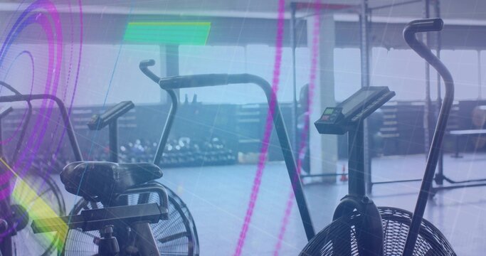 Fototapeta Featuring central air bike spinning fan with digital display in fitness studio, with dumbbell rack