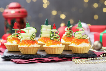 Tasty tartlets on grey textured table against blurred lights, closeup. Christmas appetizer