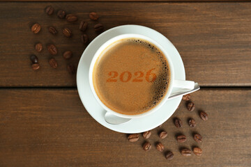 Hello New 2026 Year. Cup of coffee with numbers and roasted beans on woden table, top view