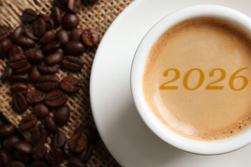 Hello New 2026 Year. Cup of coffee with numbers and roasted beans on table, top view
