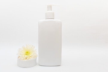 A white plastic container with a dispenser. With white flowers and cotton pads.