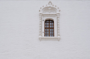 Carved window against a white wall. The territory of the Astrakhan Kremlin, the architecture of the Assumption Cathedral.