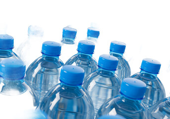 Group of clear plastic water bottles with blue caps arranged closely together isolated on transparent background