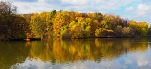 A pond in a city park in autumn. Lush, colorful foliage.