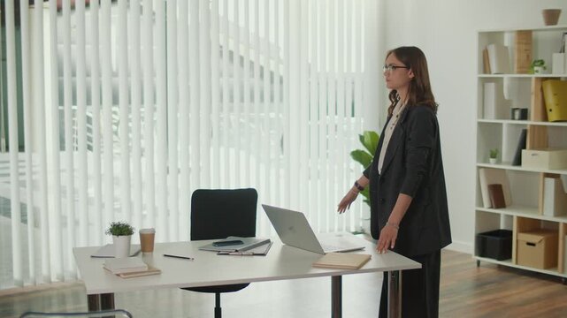 Stress Relief and Employee Wellbeing. Office Manager Performs Standing Quadriceps and Lumbar Spine Stretch at Desk to Prevent Pain, Improve Posture, add Balance to Work and Support Healthy Workplace