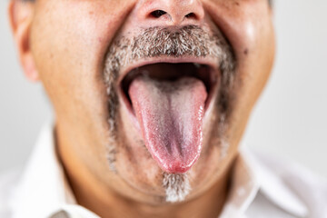 Macro portrait of a middle-aged man sticking his tongue out with mouth wide open, showing detailed texture of the tongue and surrounding facial hair.