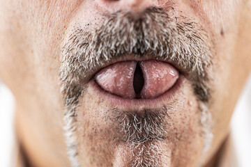 Macro close-up of a man’s mouth and mustache with the tongue rolled in a playful gesture.