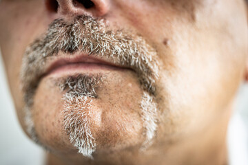 Close-up macro photograph of a man’s lower face showing detailed mustache and goatee with gray stubble.