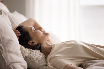 Older woman lying on back in bed with closed eyes