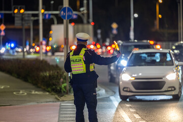 Policjant kieruje ruchem w nocy na ulicy.