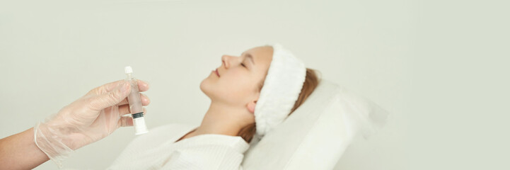 Young caucasian female receiving facial treatment with syringe in spa setting.