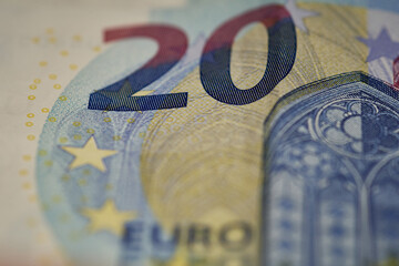 Close-up image of a 20 euro note displaying the denomination, security features, and design details with precision.