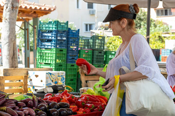 Senior woman choosing red bell pepper at market