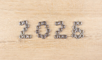Number 2026 by metal nuts on a light wooden background. 2026 year