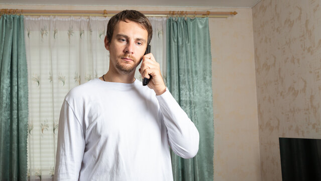 Young man talking on phone at home. - Powered by Adobe