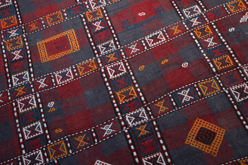 A vivid textile featuring a geometric grid of red and grey blocks