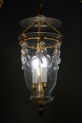 A refined glass lantern chandelier suspended by gold chains, featuring crystal beads