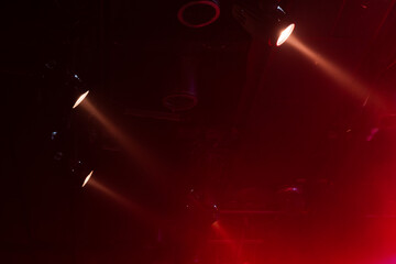Energetic concert scene featuring red spotlights cutting through haze