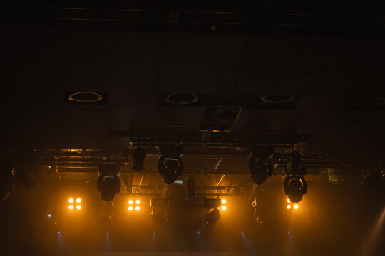 Dim, moody backstage scene with warm amber stage lights