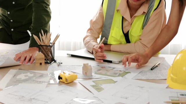 Professional engineer measuring the blueprint. Professional engineer working architectural project at studio on a table with yellow helmet and architectural equipment scatter around. Delineation.