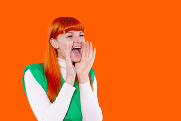 Young woman joyfully cheering with bright orange background during a fun event or celebration