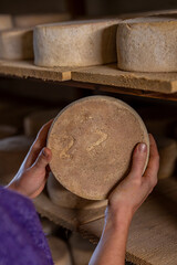 Gros plan sur des fromages en cours d’affinage dans une cave, révélant les textures naturelles, les nuances de couleur et le savoir-faire artisanal de la production fermière.