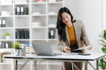 Focused Business Acumen: A diligent businesswoman, immersed in her work, meticulously reviews...