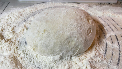 a closeup of a white bread dough on a wooden table with a blurry background