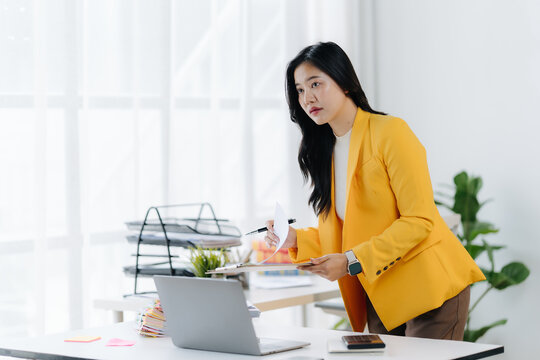 Focused Professional: A business woman, deep in concentration, analyzes data and strategizes her next move while working in her office.