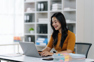 Focused Work: A woman, deeply engaged with her laptop, finds herself in an office environment, showcasing both technology and determination.