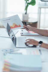 Analyzing Financial Charts at Office Desk: The scene captures an individual, deeply engaged in financial analysis, meticulously examining charts and graphs at their office desk.